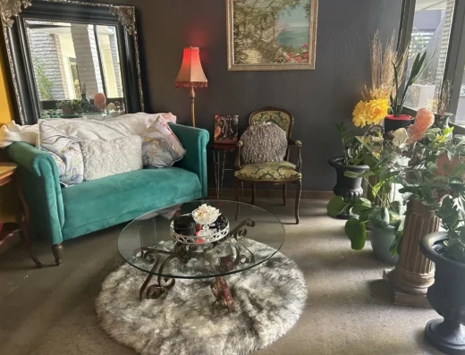 Teal velvet sofa with decorative pillows, a glass coffee table, and a fluffy fur rug in a cozy living room corner.