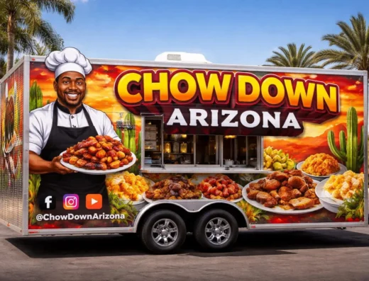 Chef in a white hat presenting a plate of fried chicken from a colorful Chow Down Arizona food truck with desert scenery in the background.