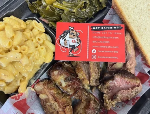 Barbecue platter with macaroni and cheese, sautéed greens, sliced ribs, and a red Got Catering card on top.