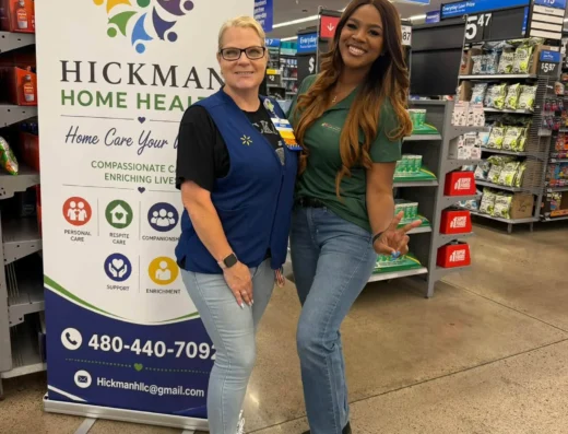 Two women smiling in a store beside a Hickman Home Health banner.