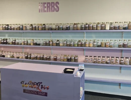 Herbal shop interior with glass jars of dried herbs on wall shelves and a purple checkout counter in the foreground