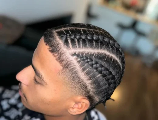Side view of a man with tight cornrow braids along the scalp and a high fade on the sides