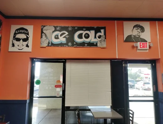 Orange walled storefront interior with three posters above a doorway a metal roll down shutter and glass doors on either side